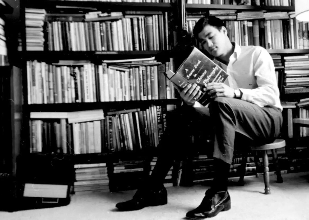 Bruce Lee in his library, reading A Source Book in Chinese Philosophy — the scholar behind the fighter